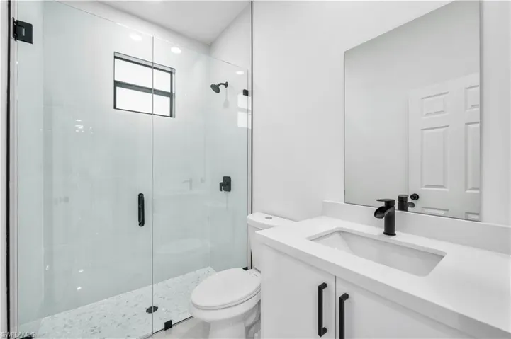 Bathroom featuring vanity with extensive cabinet space, an enclosed shower, and toilet