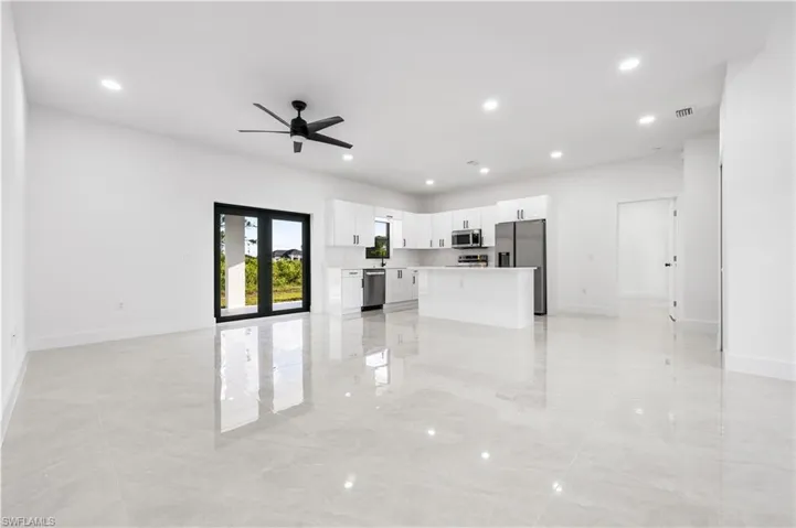Unfurnished living room featuring ceiling fan, french doors, and light tile flooring