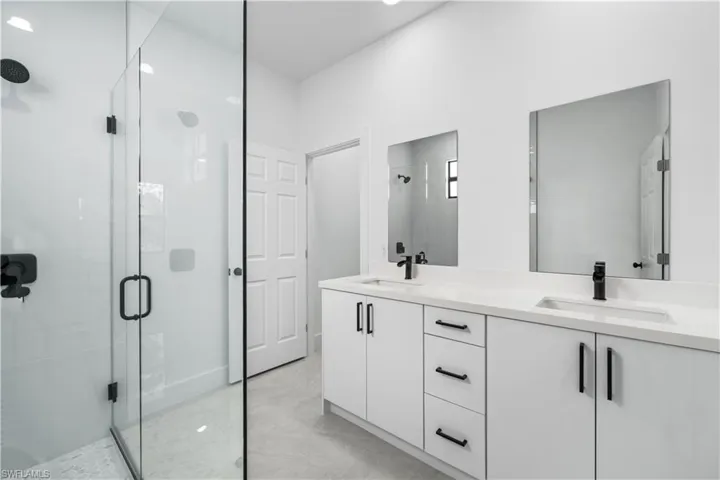 Bathroom featuring tile floors, a shower with door, oversized vanity, and double sink