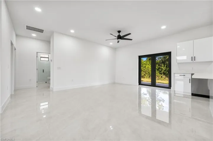 Unfurnished living room featuring ceiling fan, light tile flooring, and french doors