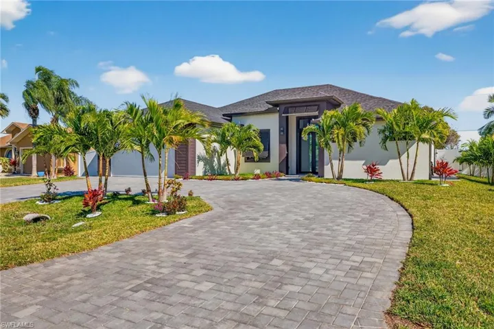 View of front of home featuring a front lawn, stucco siding, and curved driveway
