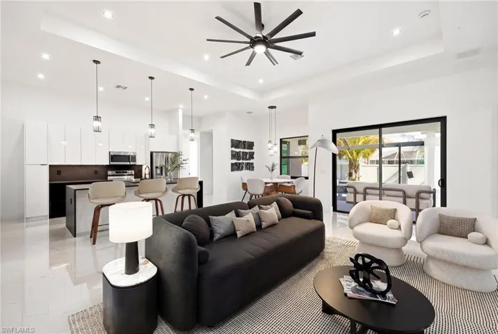 Living area with a ceiling fan, a tray ceiling, and recessed lighting