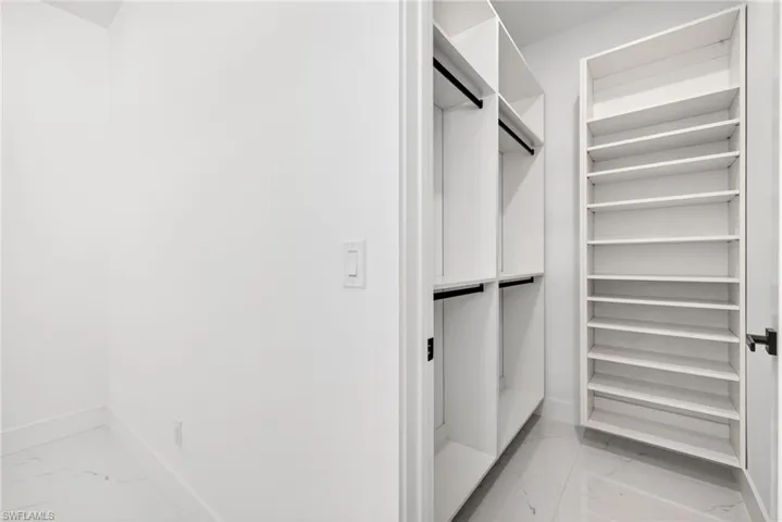 Walk in closet featuring light marble finish flooring