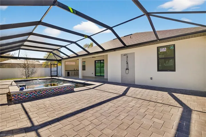 View of patio / terrace featuring a sunroom, glass enclosure, and a pool with connected hot tub