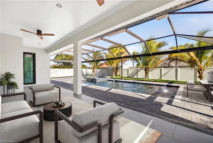 Fenced backyard with a lanai, a patio area, an outdoor hangout area, ceiling fan, and a pool with connected hot tub