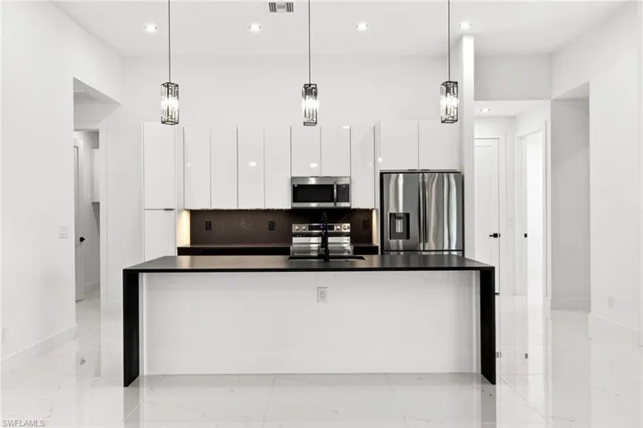 Kitchen featuring stainless steel appliances, modern cabinets, a spacious island, and white cabinets