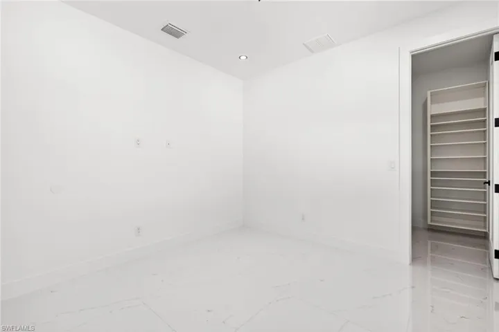 Empty room featuring light marble finish flooring and recessed lighting