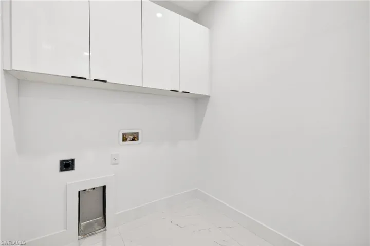 Laundry room featuring hookup for an electric dryer, cabinet space, light marble finish flooring, and hookup for a washing machine