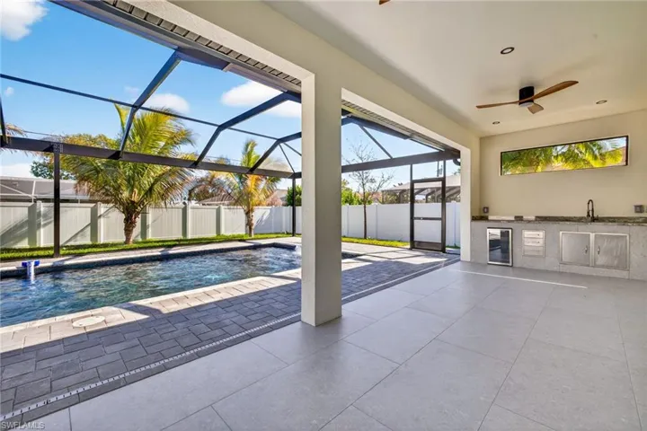 View of pool with exterior kitchen, a lanai, a fenced backyard, patio surround, and a sunroom