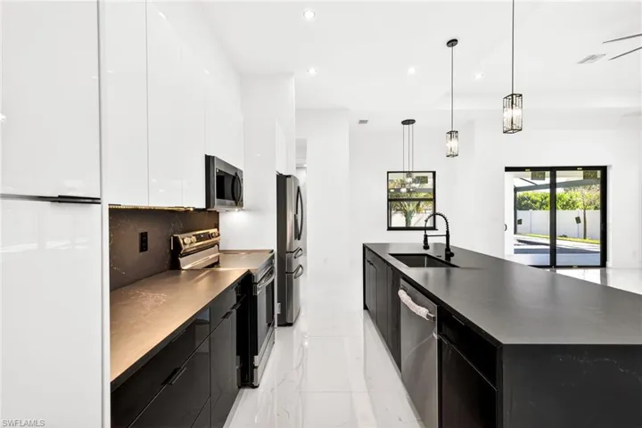 Dual tone kitchen with modern cabinets, stainless steel appliances, decorative light fixtures, a spacious island, and dual tone cabinets