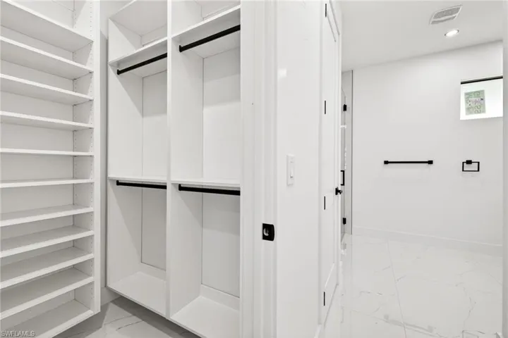 Walk in closet featuring light marble finish flooring
