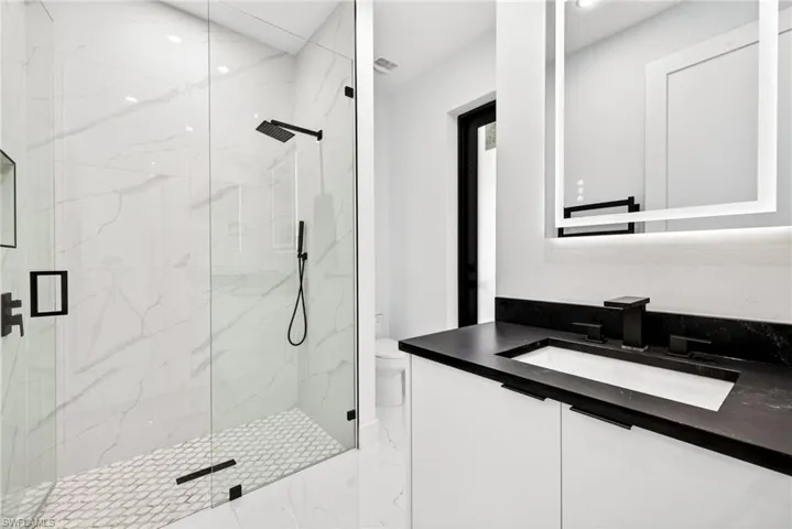 Full bath featuring a marble finish shower, vanity, and light marble finish flooring
