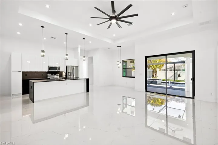 Kitchen featuring white cabinetry, a large island with sink, decorative light fixtures, stainless steel appliances, and open floor plan