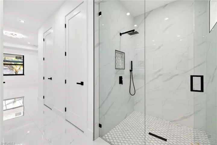 Bathroom with a marble finish shower, light marble finish floors, and recessed lighting