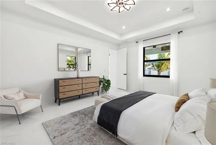 Bedroom featuring multiple windows, a tray ceiling, and recessed lighting