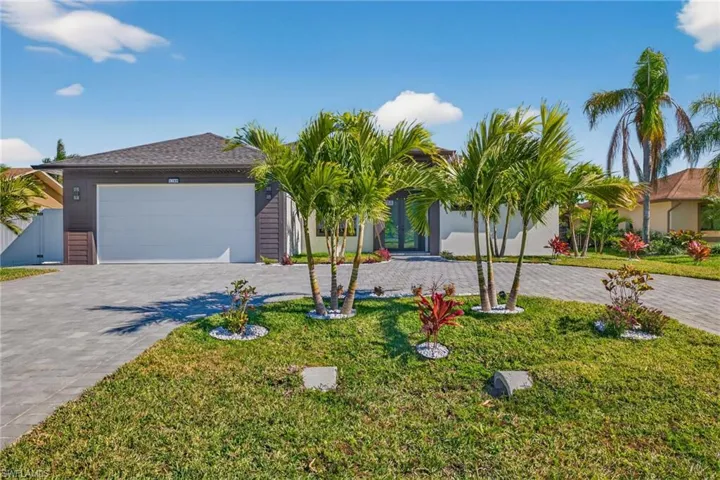 Ranch-style home with curved driveway, a front lawn, a gate, a garage, and stucco siding
