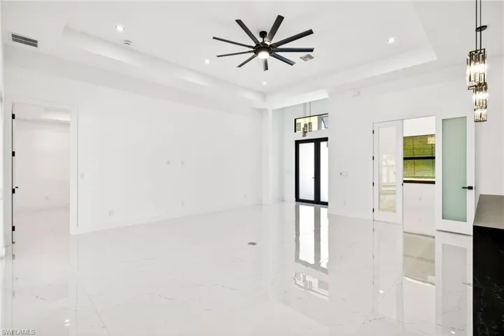 Unfurnished room featuring light marble finish flooring, french doors, a tray ceiling, recessed lighting, and a ceiling fan