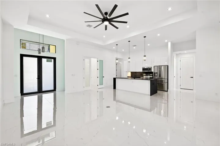 Kitchen featuring stainless steel appliances, open floor plan, french doors, white cabinets, and pendant lighting