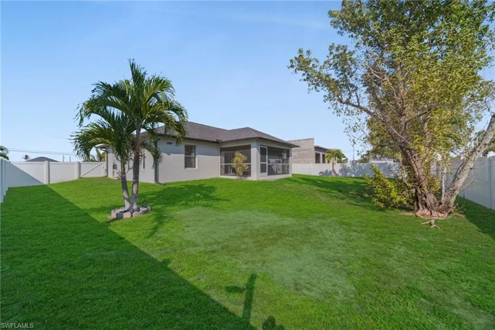 Rear view of property featuring a fenced backyard, a sunroom, and stucco siding
