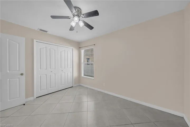 Unfurnished bedroom featuring ceiling fan, a closet, and light tile patterned floors
