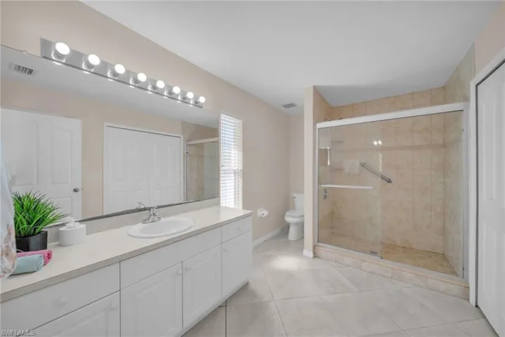 Full bath with vanity, a stall shower, light tile patterned floors, and a closet