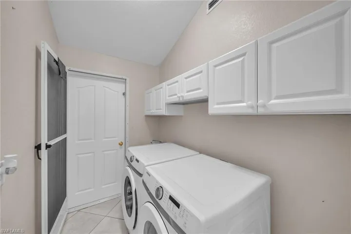 Laundry room featuring cabinet space, washing machine and clothes dryer, and light tile patterned floors
