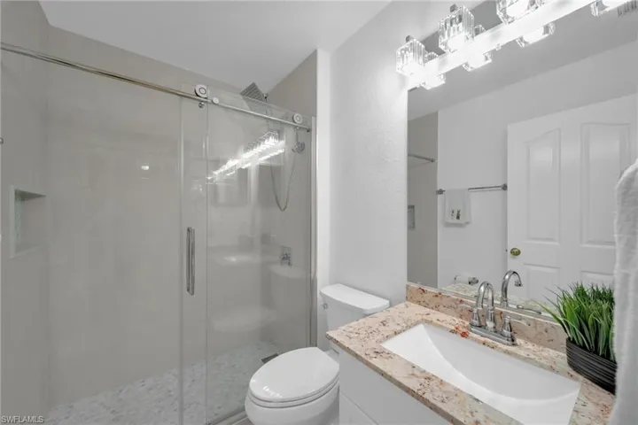 Bathroom featuring vanity, a stall shower, and a textured wall