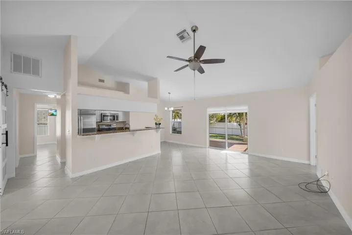 Unfurnished living room featuring a ceiling fan, light tile patterned flooring, and vaulted ceiling