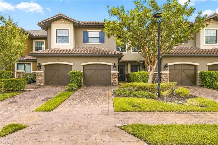Stucco exterior with stone accents, tile roofing, and arched garage doors