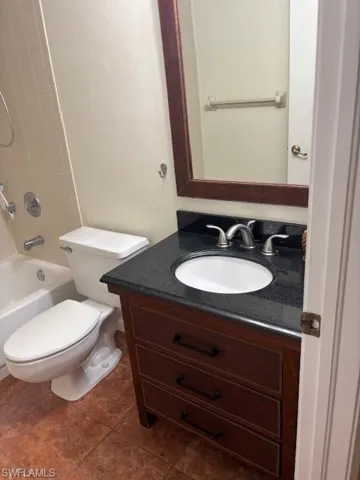 Bathroom featuring vanity, shower / tub combination, and dark tile patterned floors