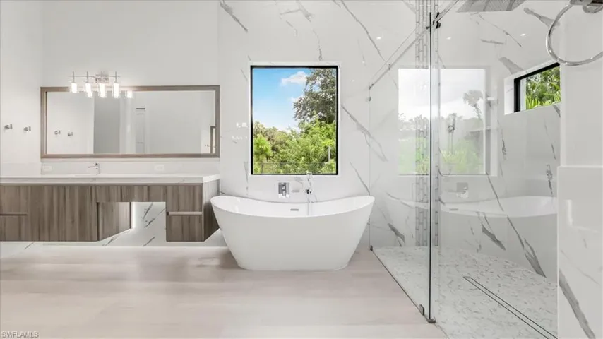 Full bath with a marble finish shower, a freestanding tub, and vanity