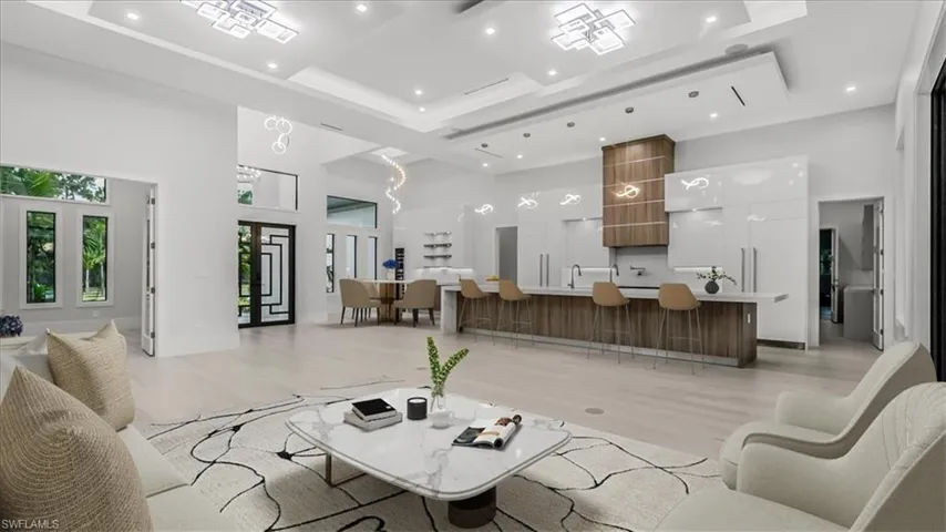 Living room with a towering ceiling, light wood-type flooring, a tray ceiling, and recessed lighting