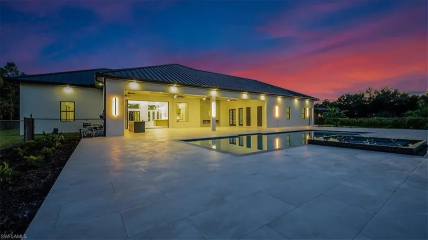 Pool at dusk with a patio, ceiling fan, and a pool with connected hot tub