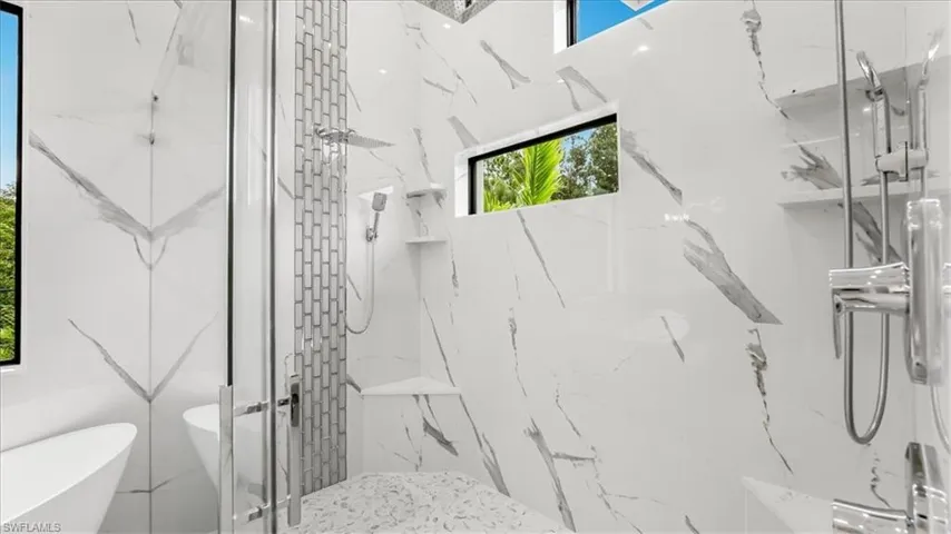 Full bathroom with a freestanding bath and a marble finish shower