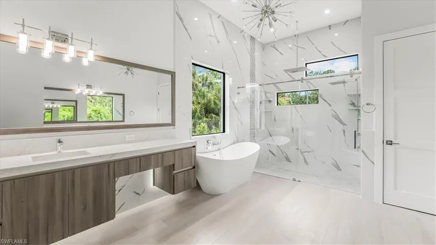 Full bathroom with a marble finish shower, a soaking tub, and vanity