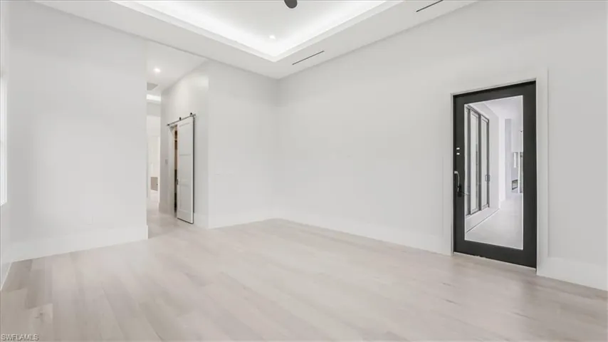 Empty room with a barn door, light wood-style floors, and recessed lighting