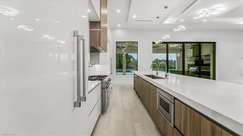 Kitchen with modern cabinets, brown cabinets, light stone counters, light wood-style flooring, and recessed lighting