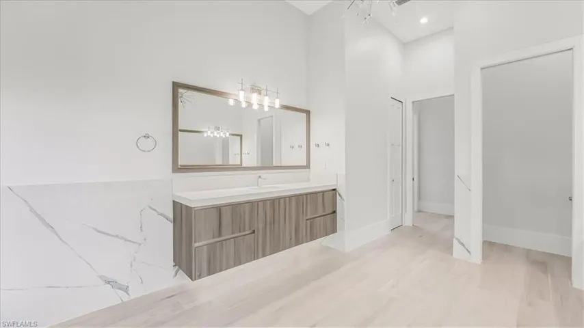Bathroom with vanity, light wood-style flooring, and a towering ceiling