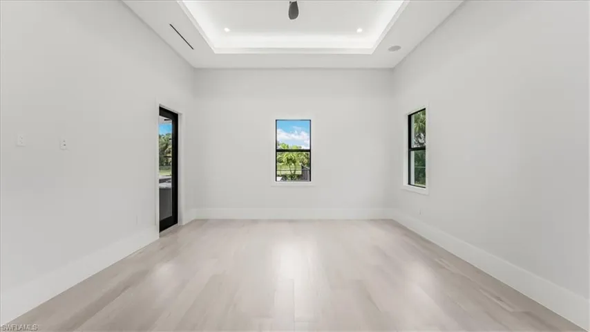 Empty room featuring light wood-style flooring and a tray ceiling
