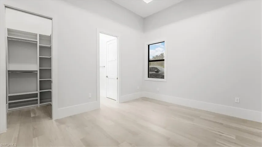 Unfurnished bedroom featuring a spacious closet and light wood-style floors