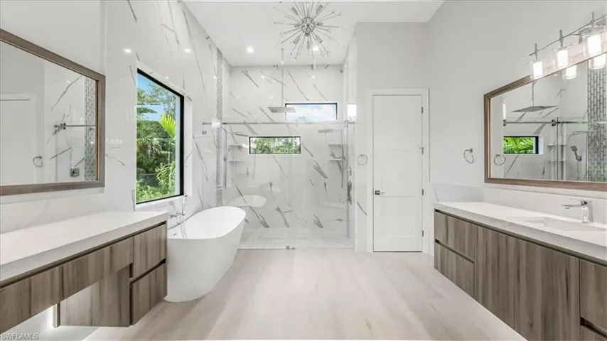 Full bathroom featuring a marble finish shower, a soaking tub, vanity, recessed lighting, and a chandelier
