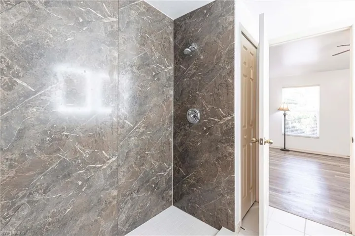 Bathroom featuring a marble finish shower and tile patterned floors