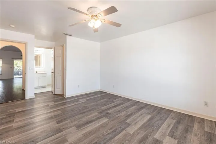Spare room featuring dark wood-style flooring, arched walkways, and ceiling fan