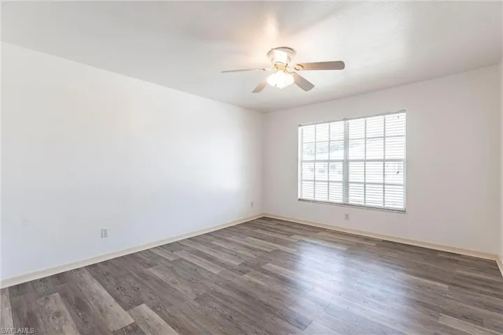 Empty room with dark wood-style flooring and ceiling fan