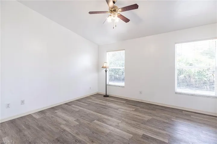 Unfurnished room featuring wood finished floors, lofted ceiling, and a ceiling fan