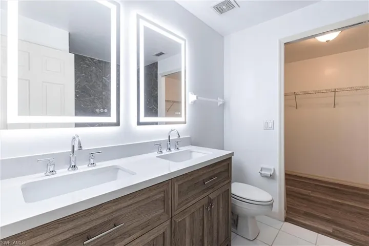 Bathroom featuring double vanity, light tile patterned floors, and a spacious closet
