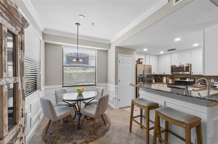 Dining room featuring a healthy amount of sunlight, an inviting chandelier, ornamental molding, and light tile floors