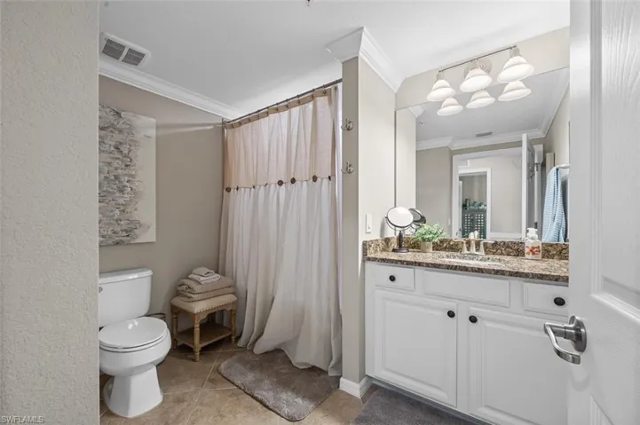 Bathroom featuring tile floors, crown molding, vanity, and toilet