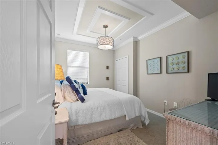 Bedroom with carpet flooring, ornamental molding, and a raised ceiling
