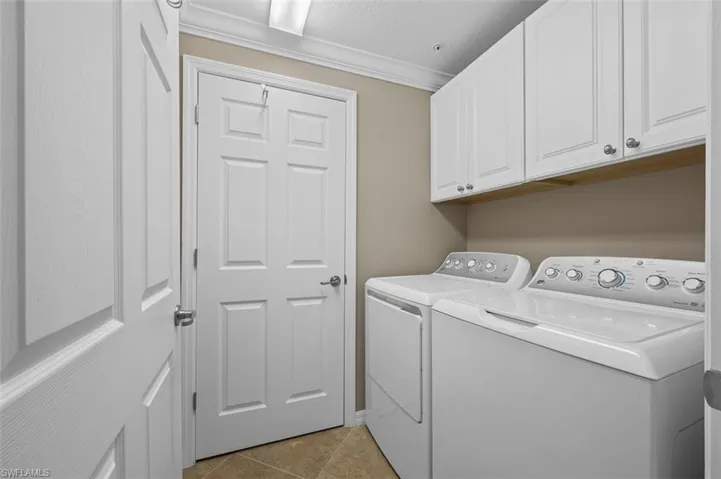 Laundry room featuring cabinets, a textured ceiling, ornamental molding, independent washer and dryer, and light tile floors